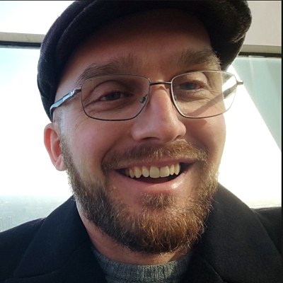 Ovidiu Neagu, smiling, wearing glasses and a flat cap